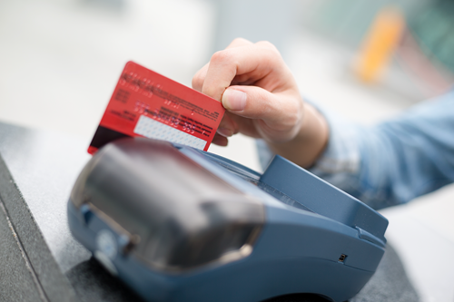 A woman slides her credit card at a store POS system to make a payment.