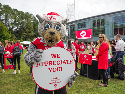 Tuffy at Red and White week holding a sign saying WE APPRECIATE YOU.