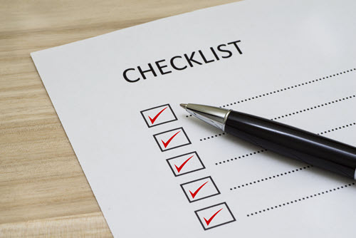 A checklist with all checklist items checked off in red and a pen resting on top of the list.