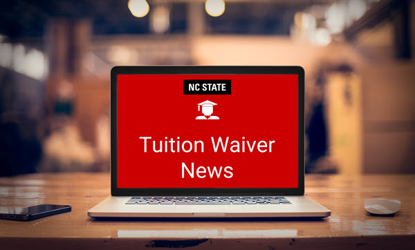 A laptop sitting on a desk. A decorative image with the NC State block logo, a graduating student icon, and the text Tuition Waiver News is on the computer screen.