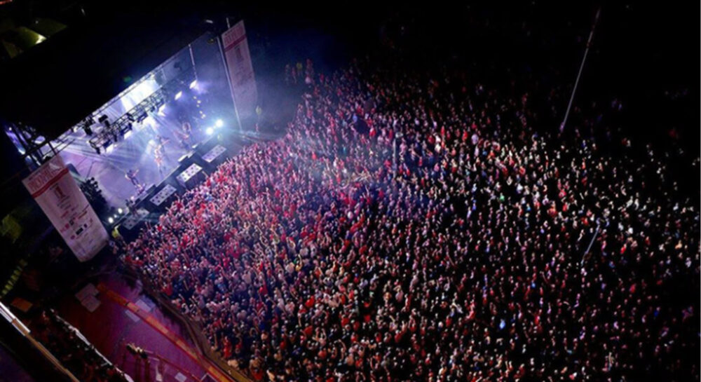A large group of people gathers to watch a concert.