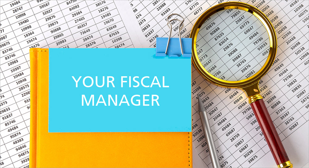 A book, pen and magnifying glass on top of financial documents. The book is labeled "Your Fiscal Manager."