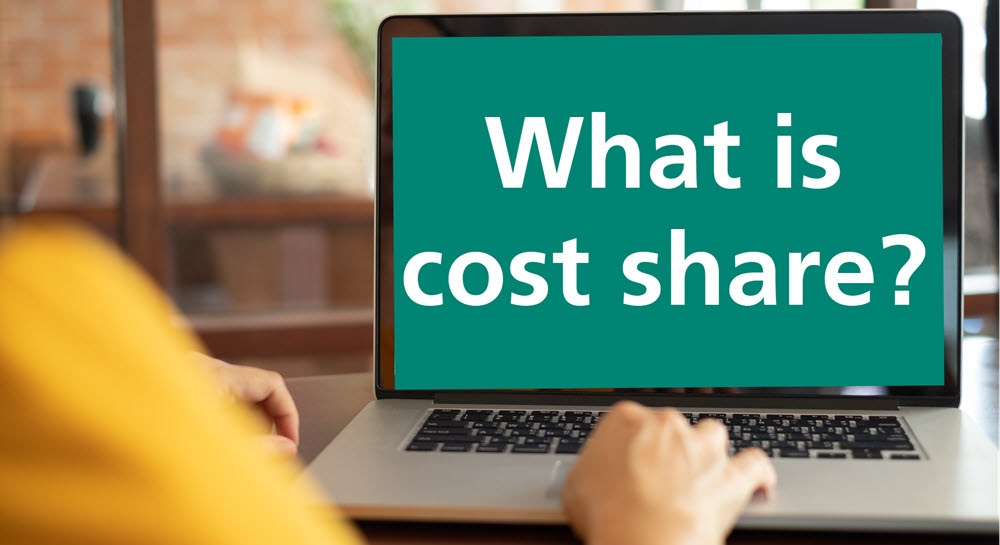 A person using a laptop, and "What is cost share?" is displayed on the screen in large text