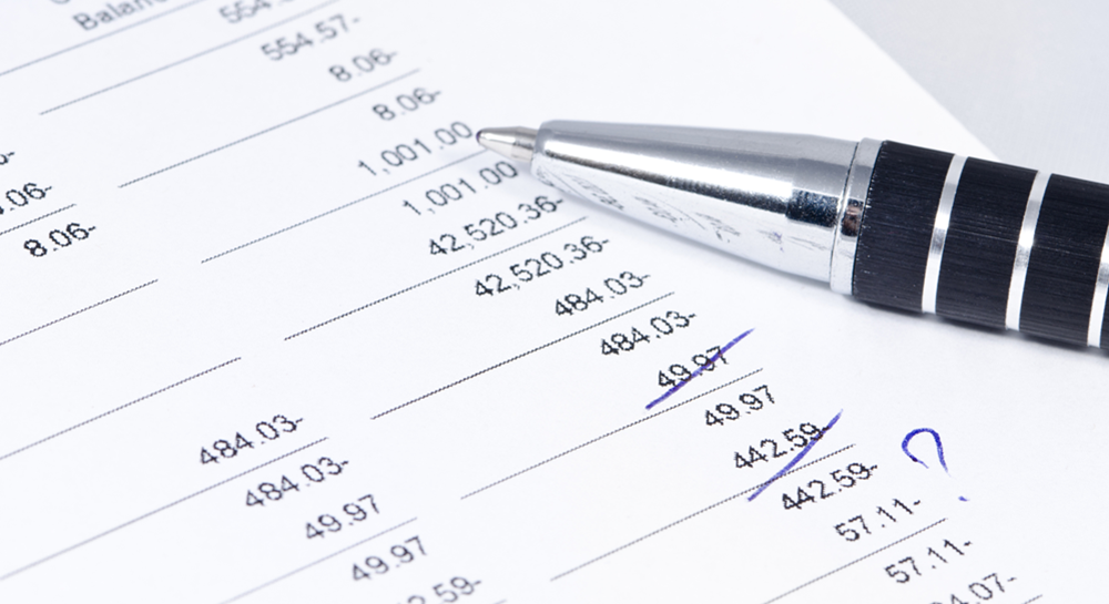 A pen resting on a printout showing account balances and expenses