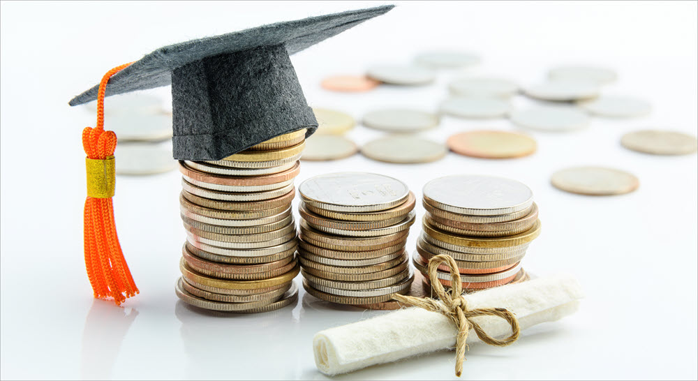 Stacks of coins with coins in the background and a simulated diploma in the foreground. The left stack of coins has a graduation cap on it.