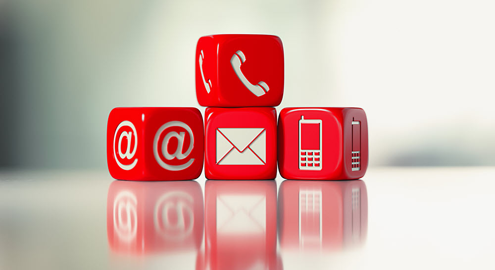 Four dice showing symbols for email, phone, cell phone, and @.