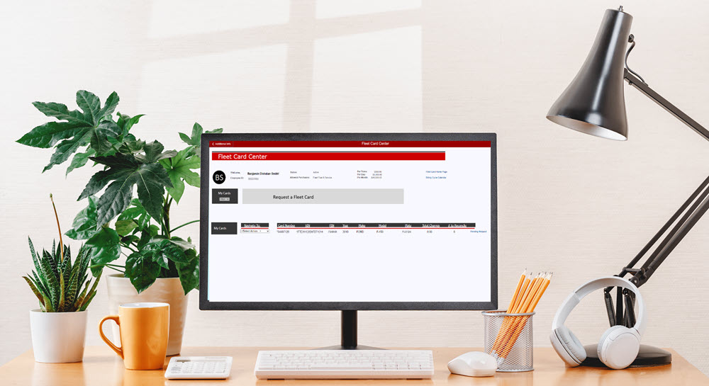 A desk workspace with a monitor showing the Fleet Card Center