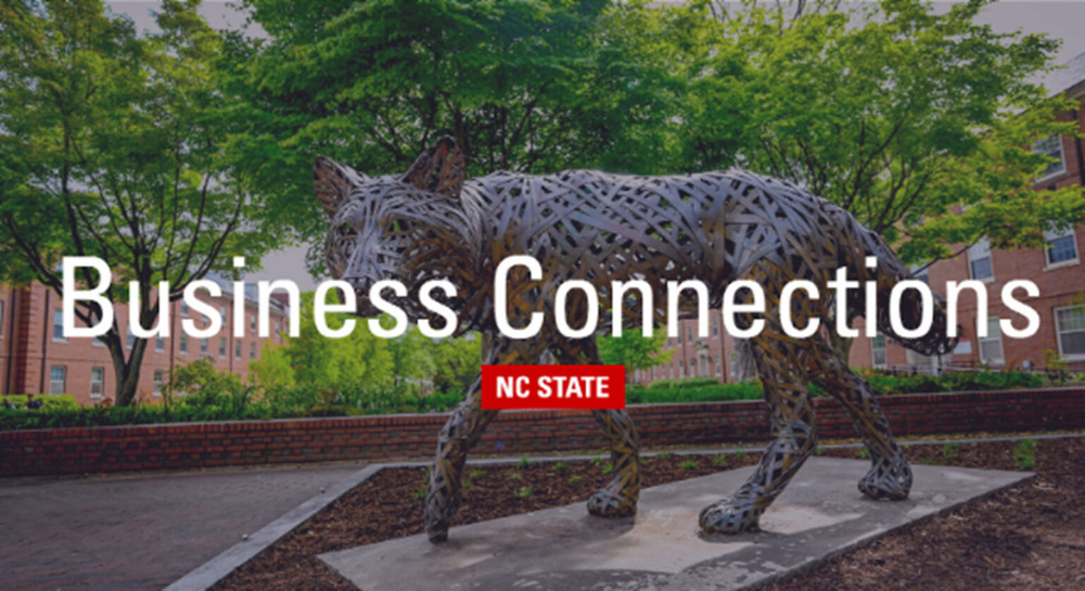 A metal wolf statue on campus with the words "Business Connections" and an NC State brick logo in the foreground