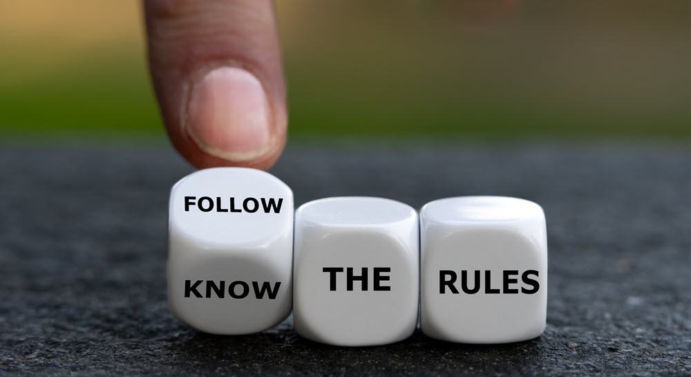 Three dice with words instead of numbers. The first di is being moved by a finger to say both "follow" and "know." The second di says "the," and the third di says "rules."