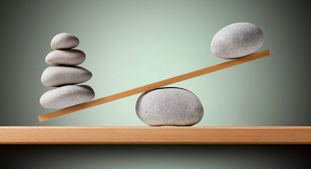 A decorative image showing rocks balancing on a scale made of wood and another rock.