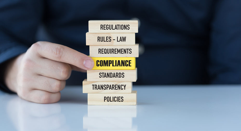 Stack of wooden blocks with the following words on each block" Regulations, rules-law, requirements, compliance, standards, transparency, policies"