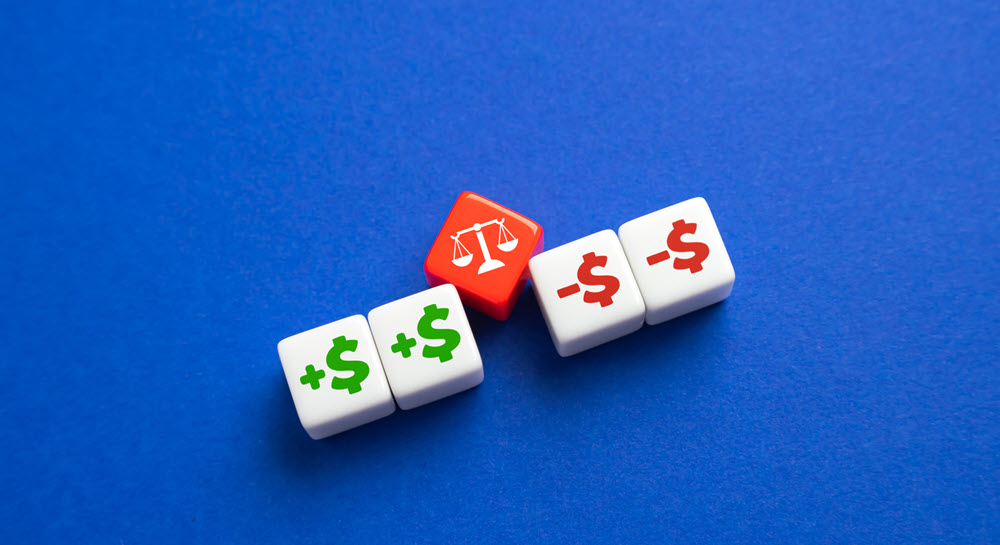 Two blocks featuring a green plus sign and dollar sign next to two blocks with a red minus sign and dollar sign. In between the sets of blocks is a red block with a white scale icon.