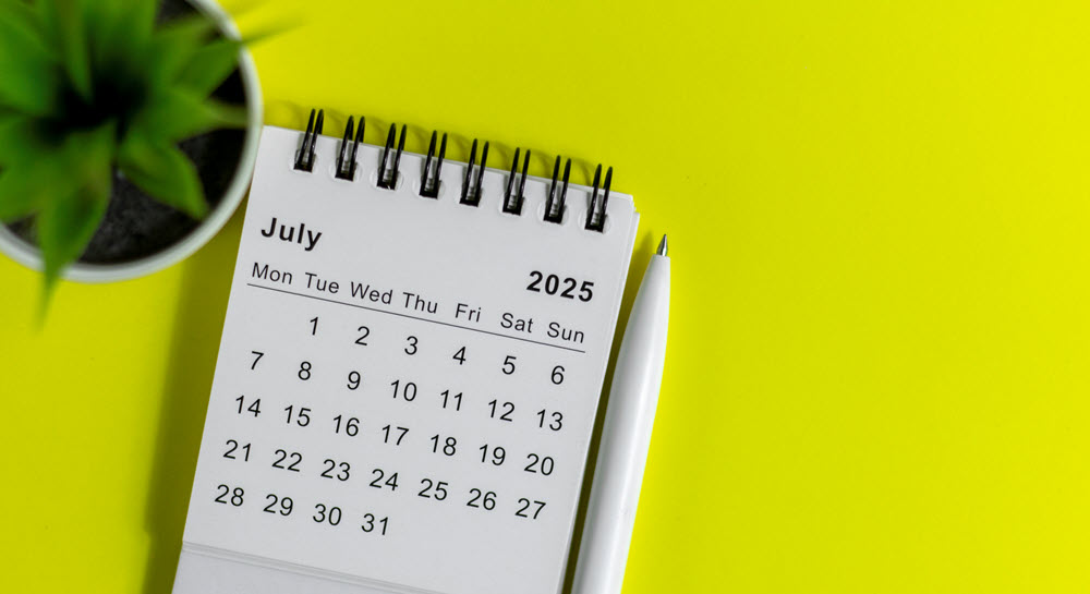 A small wirebound calendar with July 2025 displayed over a yellow background.